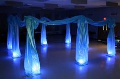 an empty room with blue lights on the floor and white drapes draped over it