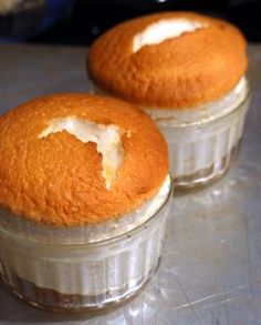 two muffins sitting on top of a table next to each other in glass containers