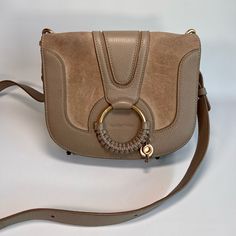 Beautiful Hana Shoulder Bag In Caramello Cowhide And Suede Cowhide With An Adjustable Strap. A Large Braided O Ring Features The Signature See By Chloe Medal. It Can Be Crossbody Or Shoulder And Has A Magnetic Top Closure. Inside Has 2 Large Compartments And One Thin One Flat Slot In The Middle And A Card Slot. It Is 8.7” Wide, 7.1” High And 2.8” Deep And Comes With The Original Duster Bag. Wear: Slight Wear On Inner And Top Suede From Rubbing Against Clothes, But No Tears Or Damage. Magnet Clasp Has A Little Wear From Opening/Closing. See By Chloe Hana, See By Chloe, O Ring, Chloe, Adjustable Straps, Bag Lady, Shoulder Bag, Ring, The Originals