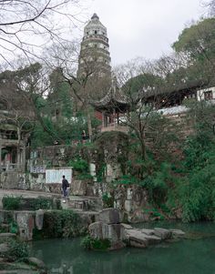 a man standing in front of a building next to a river