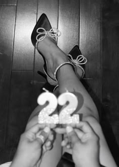 two people are holding up the number twenty one in front of their feet and wearing high heels