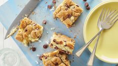 several pieces of dessert sitting on top of a blue cutting board next to a yellow plate