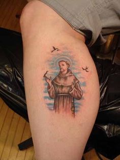 a tattoo on the leg of a person with a cross and birds flying around it