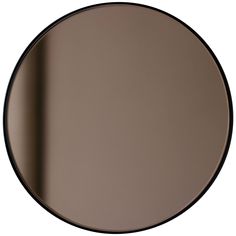 a round mirror with black trim on the bottom and an empty wall in the background