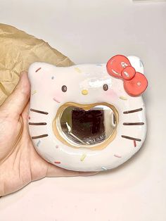 a hello kitty mask with a bow on it's head is held in someones hand