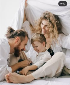 a man, woman and child laying in bed together