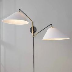 two lamps on the wall, one with a white shade and one with a black cord