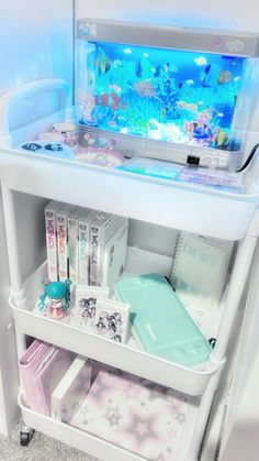 an aquarium is sitting on top of a cart with books and other items in it