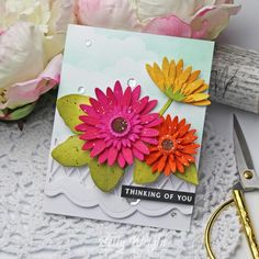 a close up of a card with flowers on it next to a pair of scissors