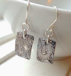 A pair of dainty rectangle silver disks hang from 2 jump rings and sterling silver ear wire. I offer the earrings in lever backs too. The silver disks are made from fine silver which is 99.9% pure silver. Each is imprinted with a delicate wave pattern. Because each one is handmade, there is a slight variation with each pair. Each earring measures approx 1 inch from the top of the ear wire. An understated design that is great for everyday wear. All metal components used are sterling silver and fi Traditional Silver Etched Earrings, Fine Silver Earrings Stamped 925, Etched Sterling Silver Dangle Earrings, Vintage Etched Sterling Silver Earrings, Bohemian Silver Etched Earrings, Photo Etching, Jewellery Pictures, Wave Earrings, Art Earrings