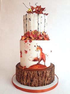 a three tiered cake decorated with red and orange leaves on a tree stump stand