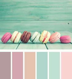 macaroons are lined up in a row on a wooden table with color swatches