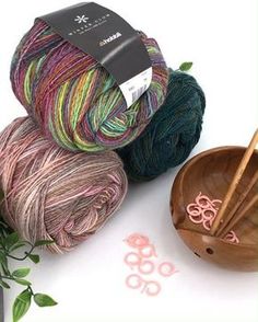 two skeins of yarn next to a wooden bowl