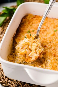 a spoon in a casserole dish with rice and parsley on the side