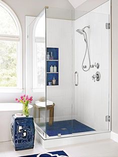 a blue and white bathroom with a shower, sink, toilet and rug on the floor