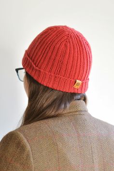 a woman wearing a red knitted beanie with an orange patch on the side