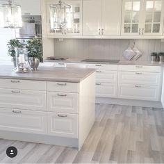 a large kitchen with white cabinets and wood flooring, is pictured in this image