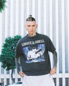 a man with tattoos standing in front of a white fence wearing a t - shirt that says ghost shell