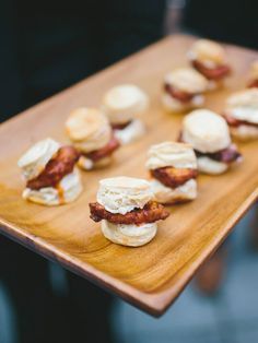 small sandwiches are arranged on a wooden tray