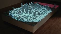 a model of a city with tall buildings and skyscrapers in the center is shown on a wooden floor