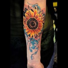 a sunflower tattoo on the left arm and shoulder with watercolor paint splatters all over it