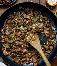 beef and onions in a skillet with a wooden spoon