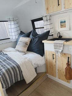 a bed sitting in the corner of a room next to a sink and cupboards