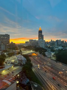 the city skyline is lit up at night with cars driving on the road and buildings in the background