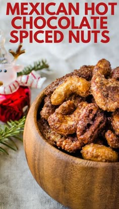 mexican hot chocolate spiced nuts in a wooden bowl on a table next to a christmas ornament