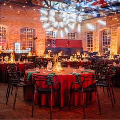 a banquet room with red and green tablecloths, black chairs, and lights