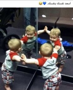 two young boys are playing in front of a mirror with their arms around each other