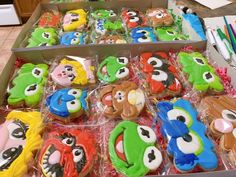 a box filled with lots of decorated cookies on top of a table next to markers and pencils