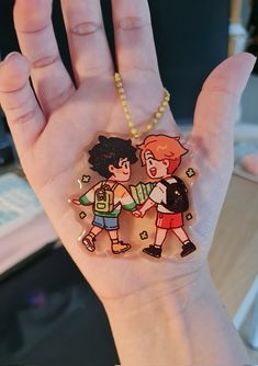 a hand holding a small plastic keychain with two cartoon characters on it's side