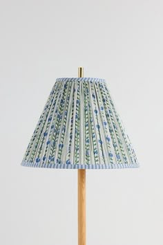 a blue and white lamp shade sitting on top of a wooden stick