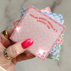 a person holding up four pink and blue checksered cards with sparkles on them