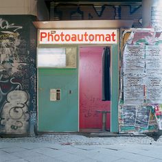 a photo shop with graffiti all over the walls and doors, in front of a brick building