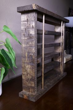 a wooden shelf sitting on top of a wooden floor next to a potted plant