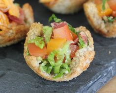 small appetizers with lettuce, tomato and cheese on them sitting on a slate platter