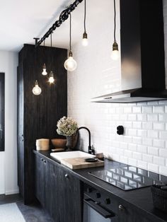 a black and white kitchen with lights hanging from the ceiling