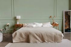 a bedroom with green walls and white bedding, two nightstands on either side