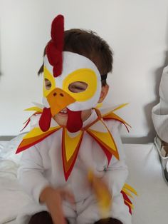 a baby wearing a chicken costume sitting on a bed