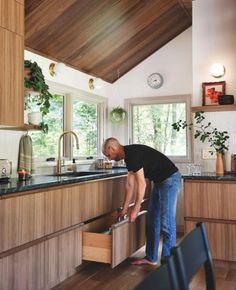 a man standing in front of a kitchen counter with an open drawer on the side