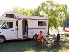 a woman sitting at a table next to a camper