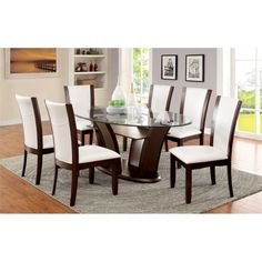 a glass dining table with white chairs and an area rug in front of the window