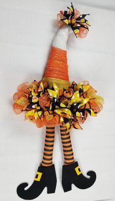 an orange and black scarecrow doll with striped socks, boots and a bow on it's head