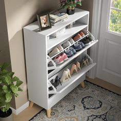 a white shoe rack with several pairs of shoes on it next to a potted plant