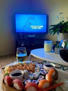 sushi platter with chopsticks and wine in front of the television screen