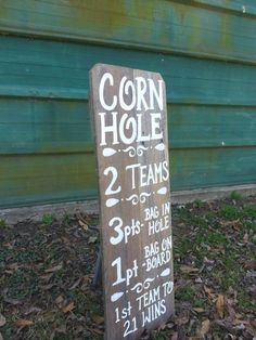 a sign that is sitting on the ground in front of a green building with writing