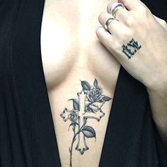 a woman with tattoos on her chest is holding onto the cross and flower tattoo design