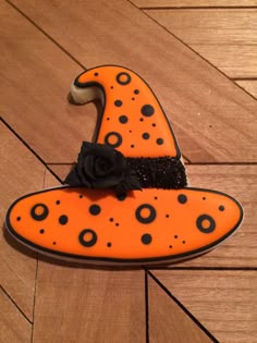 an orange witch hat with black dots and a rose on it sitting on a wooden floor